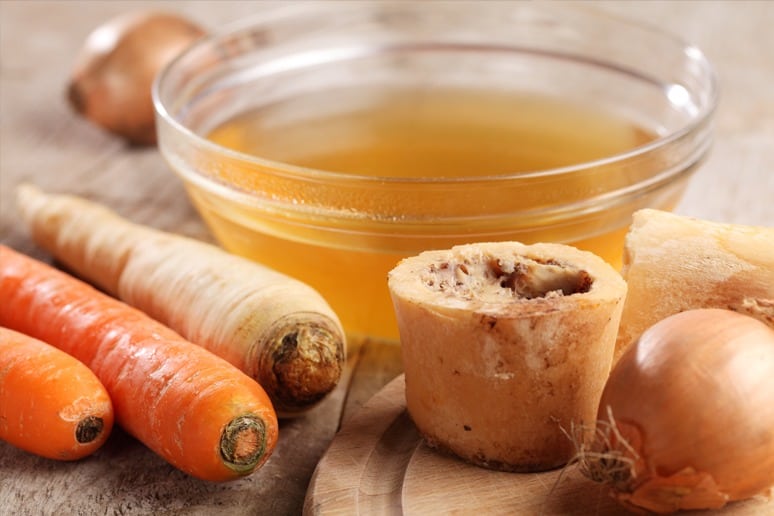 Bone Broth In Bowl Surrounded By Vegetables