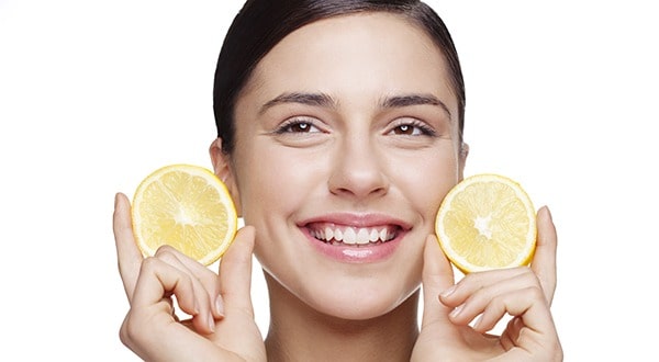 resh faced young female holding lemon slices and smiling..Light retouching, skin texture intact!"