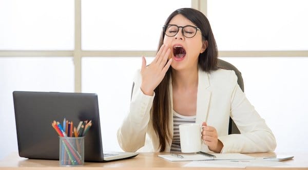 Young Woman Yawning at Work Due to Sitting All Day