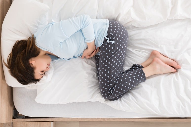 Woman Cramps Up in Bed Due to Digestion Problems