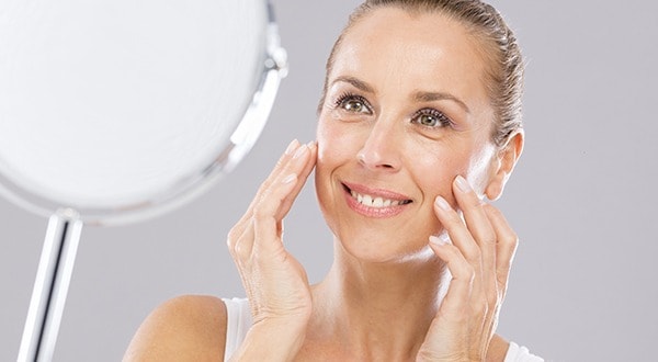 Mature woman with tenderness skin looking to the mirror.