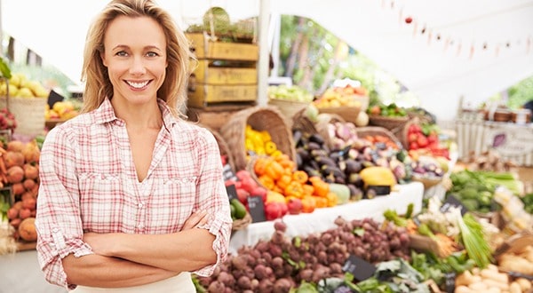 Woman Stands Smiling in Front of Fresh Organic Produce