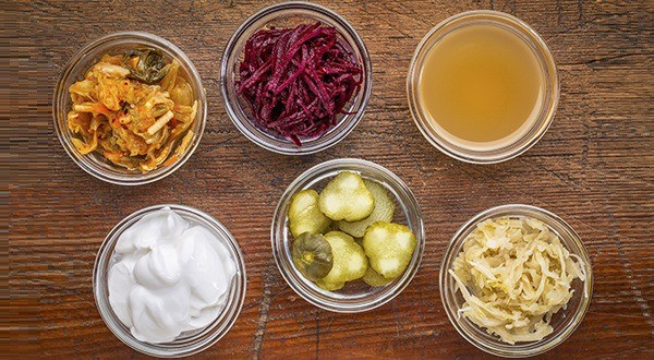 op view of glass bowls against wood: kimchi, red beets, apple cider vinegar, coconut milk yogurt, cucumber pickles, sauerkraut